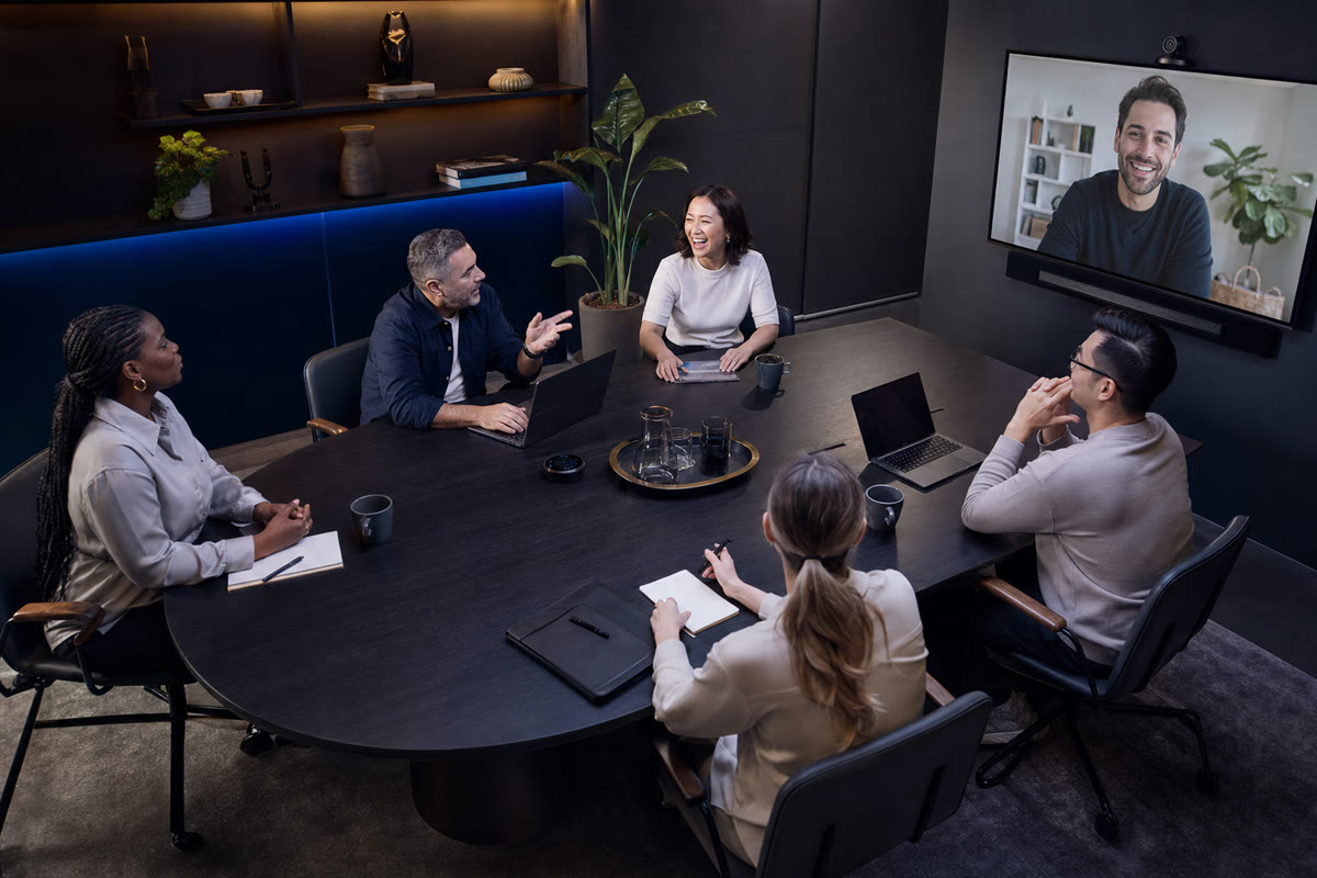 Wide view of a team around a conference table during a hybrid call, everyone visible in frame.